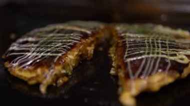 4K Okonomiyaki Japon yemeği. Soya soslu ve mayonezli. Krepi un ve suyla pişir, doğranmış lahana, yumurta, soğan ve deniz ürünleri. Monjayaki 'yi Pişirmek Bir Japon Restoranında Kızartıldı
