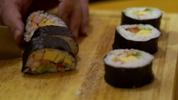 準備中の牧志のスローモーション キッチンのレストランで日本の伝統的な料理をナイフで切断男のシェフの手のクローズアップ 自家製寿司や木のテーブルの上でロールを作る — ストック動画