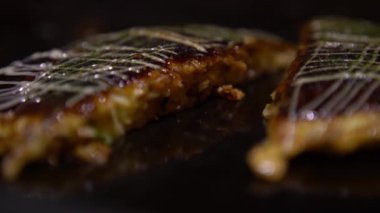 4K Okonomiyaki Japon yemeği. Soya soslu ve mayonezli. Krepi un ve suyla pişir, doğranmış lahana, yumurta, soğan ve deniz ürünleri. Monjayaki 'yi Pişirmek Bir Japon Restoranında Kızartıldı