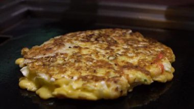 Slow Motion Soya 'yı Okonomiyaki Japon yemeğine koy. Krepi un ve suyla pişir, doğranmış lahana, yumurta, yeşil soğan ve deniz ürünleri. Monjayaki 'yi Pişirmek Bir Japon Restoranında Kızartıldı