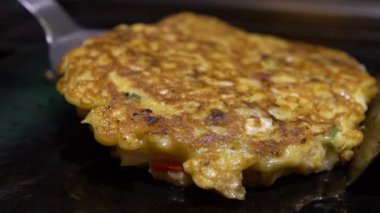 Slow Motion Cook, Okonomiyaki Japon yemeklerini çeviriyor. Krepi un ve suyla pişirdim, doğranmış lahana, yumurta, yeşil soğan ve deniz ürünleri. Monjayaki 'yi Pişirmek Bir Japon restoranında Kızartılmak - Dan
