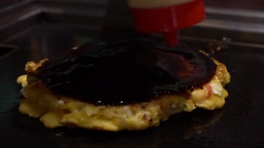 Slow Motion, Okonomiyaki Japon yemeğine mayonez ve sos ekle. Un ve suyla krep, doğranmış lahana, yumurta, yeşil soğan ve deniz ürünleri. Monjayaki 'yi Pişirmek Bir Japon Restoranında Kızartıldı