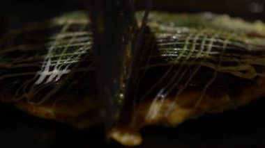 Slow Motion Okonomiyaki Japon yemeği. Soya soslu ve mayonezli. Un ve suyla krep pişir, doğranmış lahana, yumurta, soğan ve deniz ürünleri. Japon restoranında Monjayaki pişirmek...