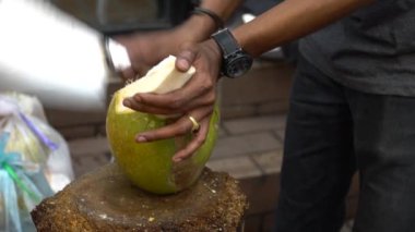 Tedarikçinin Yavaş Hareketi büyük yeşil bir hindistan cevizi kesiyor. Market caddesinde geleneksel içki. İnsanlar hindistan cevizi keser. Asya 'da egzotik içkiler. Kuala Lumpur 'da Asya tezgahı. Malezya - Dan
