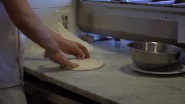 Şef, mutfakta dağınık halde pizza hamuru uçuruyor. Pizzayı malzemelerle pişirin. Pizza yapma süreci. Adam restoranda lezzetli pizza hazırlıyor. Yemek pişirme konsepti.