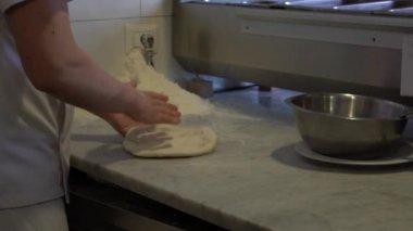 Mutfakta dağınık halde pizza hamuru uçuran şefin Yavaş Hareketi. Pizzayı malzemelerle pişirin. Pizza yapma süreci. Adam restoranda lezzetli pizza hazırlıyor. Yiyecek konsepti - Dan