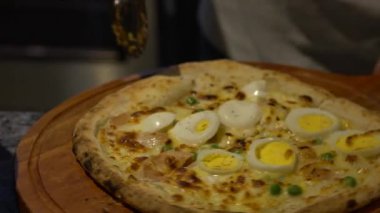 Yavaş çekim Şef İtalyan restoranının mutfağında lezzetli bir pizzayı kesiyor. Adam domatesli, macunlu, yumurtalı, yeşil bezelyeli organik pizza yapıyor.