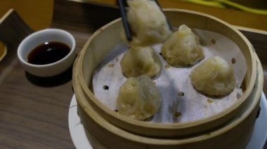 Lokantada hamur tatlısı yemek için yemek çubuğu kullanmanın yavaş hareketi. Geleneksel Çin yemekleri Şangay 'da Çin yemeği olarak servis edilir. Küçük buharlı sepetlerde servis edilen küçük lokma büyüklüğünde yiyecekler.