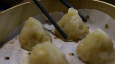 Lokantada hamur tatlısı yemek için yemek çubuğu kullanmanın yavaş hareketi. Geleneksel Çin yemekleri Şangay 'da Çin yemeği olarak servis edilir. Küçük buharlı sepetlerde servis edilen küçük lokma büyüklüğünde yiyecekler.