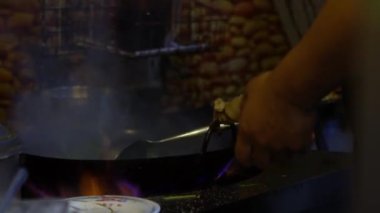 Slow Motion of Man, Tayvan restoranının mutfağında sebze pişiriyor. Çinli aşçı tavada geleneksel yemekleri pişiriyor ve karıştırıyor. Lezzetli Asya yemekleri yiyen insanlar.