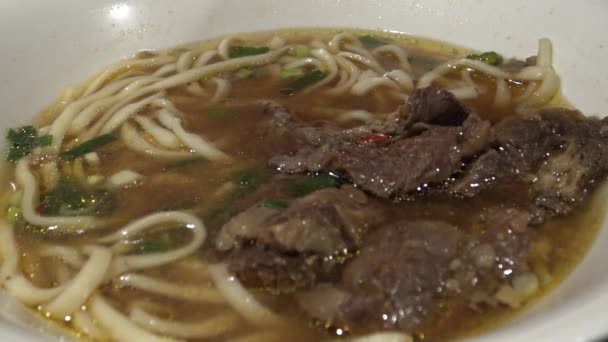 アジア料理店では 4K人が夕食に牛肉麺を食べています 台湾の伝統的な中華料理を食べるための棒を使用しています — ストック動画