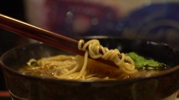 スローモーションの人々はアジアのレストランで夕食のための牛肉麺のボウルを食べる 台湾の伝統的な中華料理を食べるための棒を使用しています — ストック動画