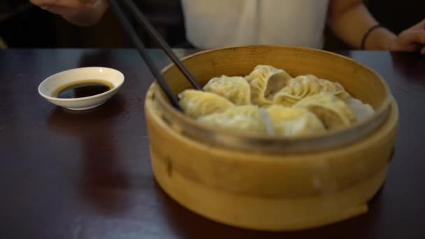 4Kアジアの女性は レストランで醤油に団子を浸します 台湾で提供される伝統的な中華料理を食べてください 蒸し籠段で提供される食品の小一口サイズの部分として調製 — ストック動画