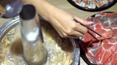 Yavaş hareket et, çiğ et ve çubuk et. Çin 'de çörek şeklinde pirinç tencereli sıcak çömlek. Pekin 'de Çin yemeği. İnce dilimlenmiş et ve sebzeler suda kaynatıldı.
