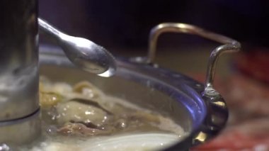 Slow Motion geleneksel Pekin usulü Çin usulü pirinç kaplı çömlek. Çiğ ve taze malzemelerle dolu yemek masası. Çin 'de meşhur bakır kavanozlarda nefis sığır eti. Yiyecek konsepti - Dan