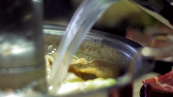 慢动作添加汤传统的北京风格的中国火锅与甜甜圈形状的黄铜锅 用生鲜配料烹调餐桌 中国著名铜罐火锅中的美味牛肉 — 图库视频影像