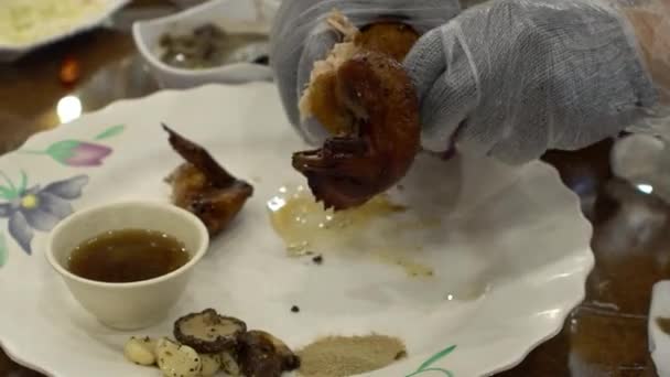 台湾の山のレストランで伝統的な鶏料理を準備するシェフの手のクローズアップ 粘土オーブンで有名なローストチキン 食べ物の一部を切るために手袋で手を使用してアジアの男 — ストック動画