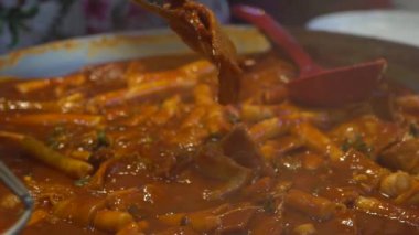 Lezzetli Tteok-bokki yapan Koreli yemek satıcıları yavaş hareket ediyor. Uzun, beyaz, silindir şeklinde tteokmyeon ya da garae-tteok denilen pirinç kekleri. Busan-Dan 'deki Gukje Uluslararası Pazarı