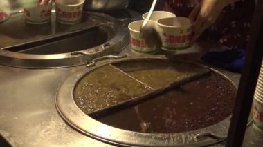 İnsanlar Jiufen Old Caddesi 'ndeki gece pazarından yemek alıp yiyorlar. Tayvan' ın Keelung kenti yakınlarındaki Chiufen şehrinde lezzetli yemekleri olan ünlü bir pazar yeri.