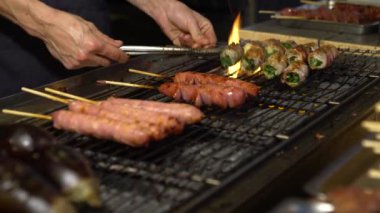 4K Satıcısı Tayvan usulü domuz pastırması pişiriyor. Asya gece pazarında çelik ızgarada taze soğan sarısı. İnsanlar popüler et ızgara barbekü pişirdi. Kömürün alevi. Ünlü bir pazar yeri. Lezzetli yemek Dan.