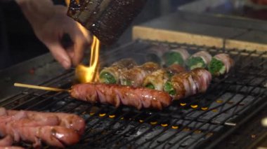 Slow Motion Sendor, Asya 'nın gece pazarındaki ızgarada domuz pastırması, taze soğan dürümü pişiriyor. İnsanlar popüler et ızgara barbekü pişirdi. Kömürün alevi. Ünlü bir pazar yeri. Lezzetli yemek Dan.