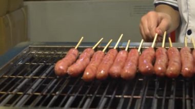 Ağır çekim. Asya 'daki Taipei Gece Pazarı' nda popüler barbekü sosisi pişiren Asyalılar.