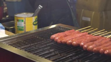 Ağır çekim. Asya 'daki Taipei Gece Pazarı' nda popüler barbekü sosisi pişiren Asyalılar.