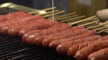 Ağır çekim. Asya 'daki Taipei Gece Pazarı' nda popüler barbekü sosisi pişiren Asyalılar.