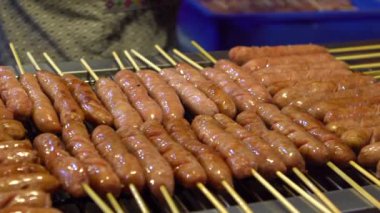 Ağır çekim. Asya 'daki Taipei Gece Pazarı' nda popüler barbekü sosisi pişiren Asyalılar.