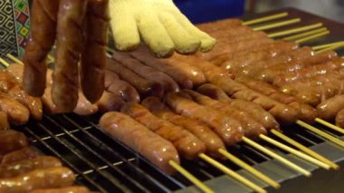 Ağır çekim. Asya 'daki Taipei Gece Pazarı' nda popüler barbekü sosisi pişiren Asyalılar.