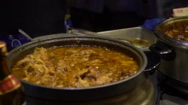 Asya 'daki yol kenarındaki tezgahlarda domuz yahnisi pişiren satıcının Yavaş Hareketi. Çin usulü lezzetli et. Taipei 'deki gece marketlerinde atıştırmalık olarak satılıyor. Çin-Dan 'de popüler Asya yemekleri