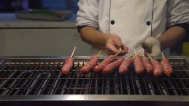 Asya 'daki Taipei Gece Pazarı' nda popüler barbekü sosisi pişiren 4K Asyalı insanlar.