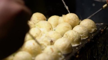 Slow Motion Japon satıcı sıcak tava Japonya üzerine bir Takoyaki hazırlayın. Yerel sokak yemeklerinde ahtapotla popüler kızarmış topları pişirme işlemi. Asya 'da gece pazarında top şeklinde yemek yapmak.