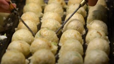 Slow Motion Asyalı satıcı lezzetli bir Takoyaki hazırla. Buğday unlu hamur hamuru hamurundan yapılmış popüler Top şeklinde Japon aperatifini pişirme ve özel kalıplı tavada pişirme işlemi
