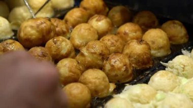 Slow Motion Asyalı satıcı lezzetli bir Takoyaki hazırla. Buğday unlu hamur hamuru hamurundan yapılmış popüler Top şeklinde Japon aperatifini pişirme ve özel kalıplı tavada pişirme işlemi