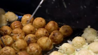 Slow Motion Japon satıcı sıcak tava Japonya üzerine bir Takoyaki hazırlayın. Yerel sokak yemeklerinde ahtapotla popüler kızarmış topları pişirme işlemi. Asya 'da gece pazarında top şeklinde yemek yapmak.