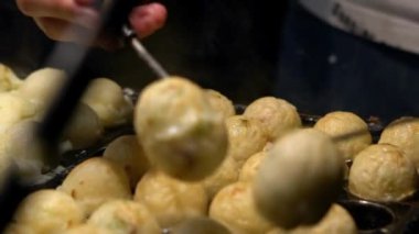 Slow Motion Asyalı satıcı lezzetli bir Takoyaki hazırla. Buğday unlu hamur hamuru hamurundan yapılmış popüler Top şeklinde Japon aperatifini pişirme ve özel kalıplı tavada pişirme işlemi