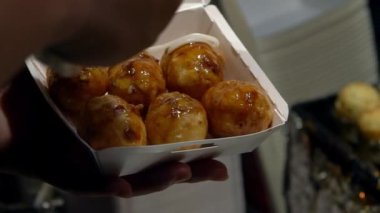 Slow Motion Japon satıcısı lezzetli bir Takoyaki hazırla. Aşçı yerel deniz ürünlerindeki ahtapotlu kızarmış toplara mayonez koyar. Asya 'nın gece pazarında Asya Balosu şeklinde yemek yapıyorum.