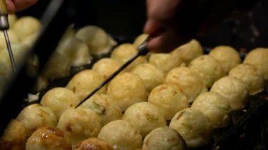 Slow Motion Asyalı satıcı lezzetli bir Takoyaki hazırla. Buğday unlu hamur hamuru hamurundan yapılmış popüler Top şeklinde Japon aperatifini pişirme ve özel kalıplı tavada pişirme işlemi