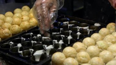 Slow Motion Asyalı satıcı lezzetli bir Takoyaki hazırla. Buğday unlu hamur hamuru hamurundan yapılmış popüler Top şeklinde Japon aperatifini pişirme ve özel kalıplı tavada pişirme işlemi