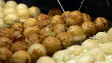 Slow Motion Japon satıcı sıcak tava Japonya üzerine bir Takoyaki hazırlayın. Yerel sokak yemeklerinde ahtapotla popüler kızarmış topları pişirme işlemi. Asya 'da gece pazarında top şeklinde yemek yapmak.