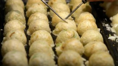 Japon satıcı sıcak tava Japonya 'da bir Takoyaki hazırlıyor. Yerel sokak yemeklerinde ahtapotla popüler kızarmış topları pişirme işlemi. Asya 'da gece pazarında top şeklinde yemek yapmak.