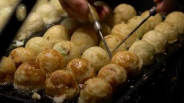 Japon satıcı sıcak tava Japonya 'da bir Takoyaki hazırlıyor. Yerel sokak yemeklerinde ahtapotla popüler kızarmış topları pişirme işlemi. Asya 'da gece pazarında top şeklinde yemek yapmak.