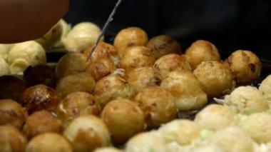 Asyalı satıcı lezzetli bir Takoyaki hazırla. Buğday unlu hamur hamuru hamurundan yapılmış popüler Top şeklinde Japon aperatifini pişirme ve özel kalıplı tavada pişirme işlemi