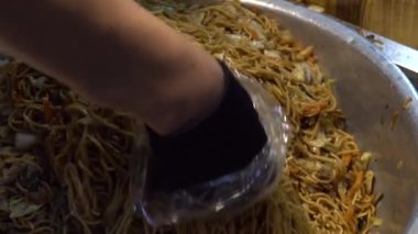 Yavaş çekim gören Asyalı dükkan sahibinin eli geleneksel kızarmış erişteleri Taipei sokak pazarındaki insanlara satmak için alır. Tayvan-Dan 'in ünlü pazarında bir erkek yiyeceği satıyor.