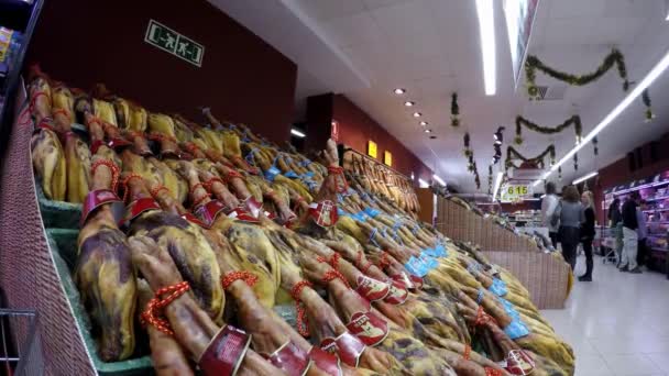 スペイン 12月 2016 スペインで異なる乾燥ポーク太ももを持つスーパーマーケット 食料品店でのスペイン料理のジャモン イベリア豚の生肉のショッピング 市場販売乾燥硬化ハムダン — ストック動画