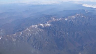 4K hava yoluyla seyahat ediyor. Gökyüzünün harika manzarası, bulutlar ve yukarıdan güzel kar dağları, bir uçak penceresinden görüldüğü gibi - Dan