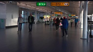 Amsterdam, Hollanda-05 Aralık 2016: 4K yolcuları Amsterdam Schiphol Uluslararası Havalimanı 'nda yürüyüş yapıyor. İnsanlar modern terminal kapılarında uçmak için yürüyorlar. Avrupa havaalanları - Dan