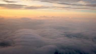 4K hava yoluyla seyahat ediyor. Gökyüzünün harika manzarası ve yukarıdan güneşli bulutlar, günbatımlı bir uçak penceresinden görüldüğü gibi.