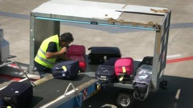 Bari, İtalya-24 Eylül 2018: Havaalanı personeli bavulları bir uçağın içine yüklüyor. Taşıyıcı bant uçağının bagajı. Kalkış terminalinde yolcu bavullarını düzenleyen bir işçi.